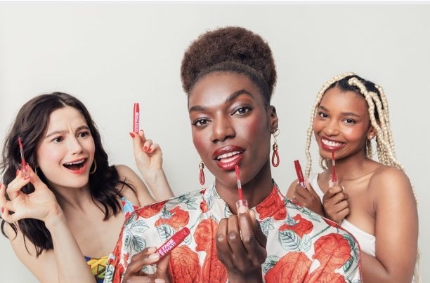 Three models with different skin tones wearing lip product