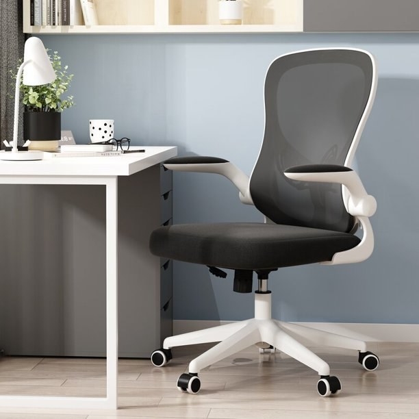 White framed desk chair with black cushion and mesh backing, in front of white desk