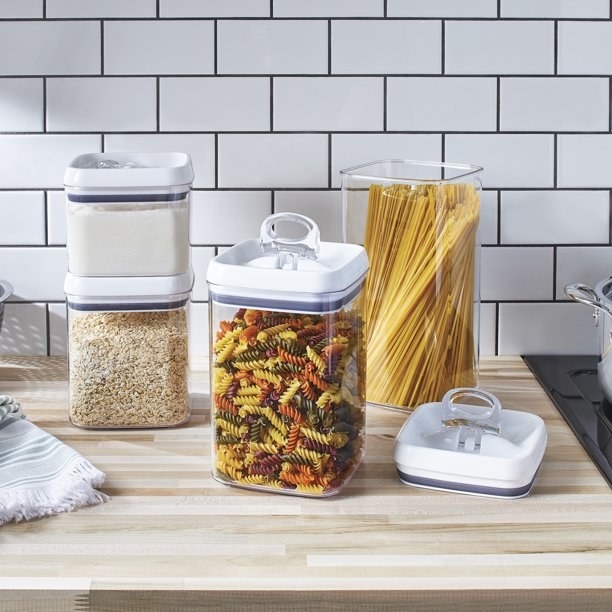 the four containers filled with pasta and grains on a countertop