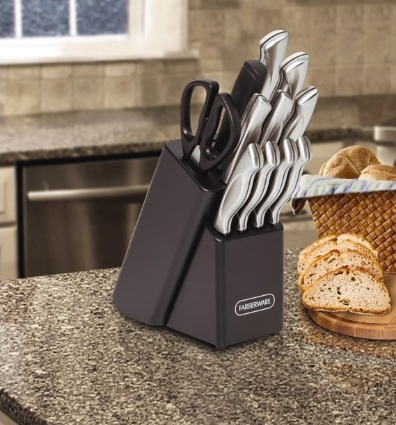 the black block and silver knives on a counter with a loaf of bread