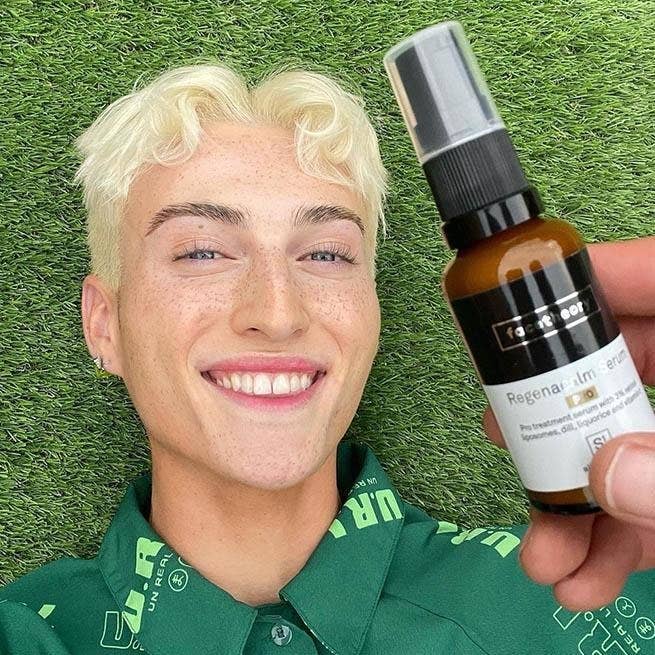 a model laying in grass with the serum bottle