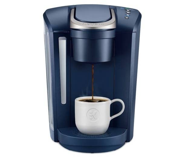 the dark blue coffee maker brewing into a white cup