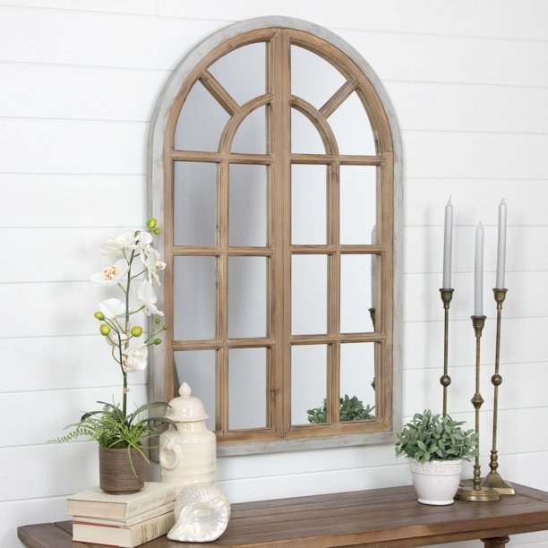 the mirror in the shape of an arched window with two panels, hung on a wall