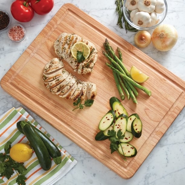 the cutting board with chicken and vegetables on a counter