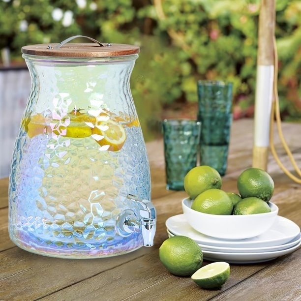 the colorful glass jar on an outdoor table next to a bowl of limes