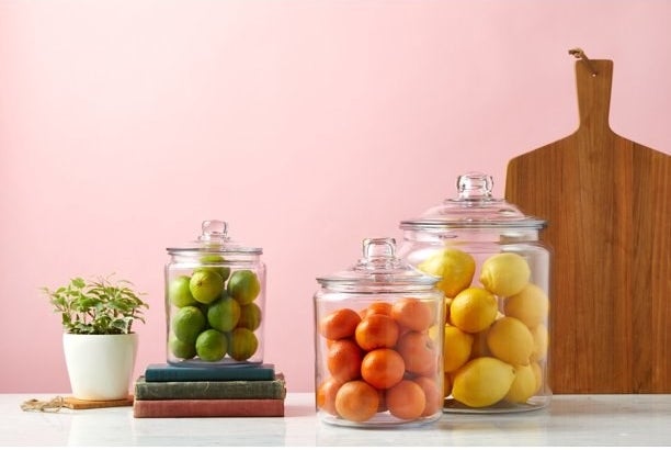 three of the variously sized glass jars filled with citrus on a decorated counter