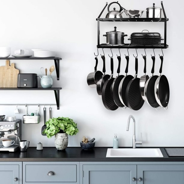 the black wall rack full of pots and pans in a decorated kitchen