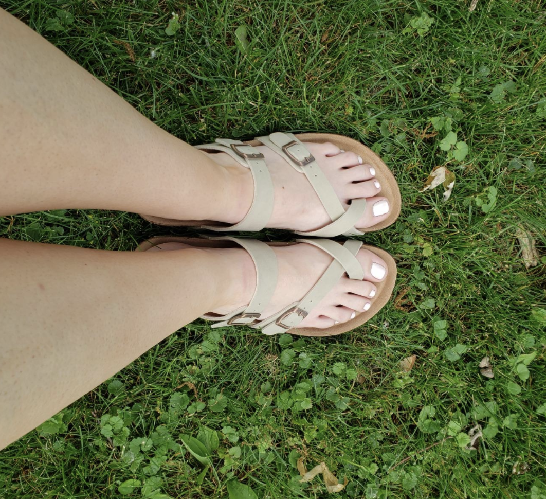 a reviewer wearing the sandals in beige on grass