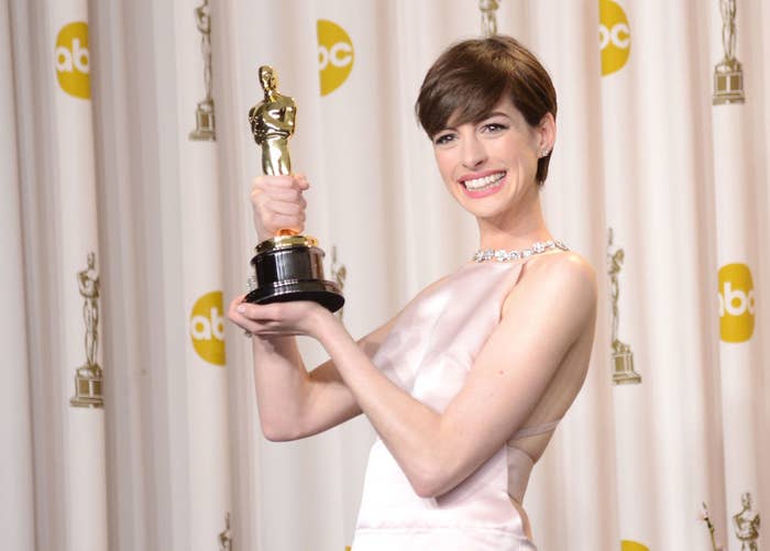 Anne Hathaway holding up her Oscar