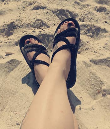 reviewer wearing the sandals in black at the beach