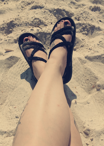 a reviewer photo of the sandals in black being worn at the beach