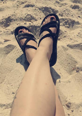 a reviewer photo of the sandals in black being worn at the beach