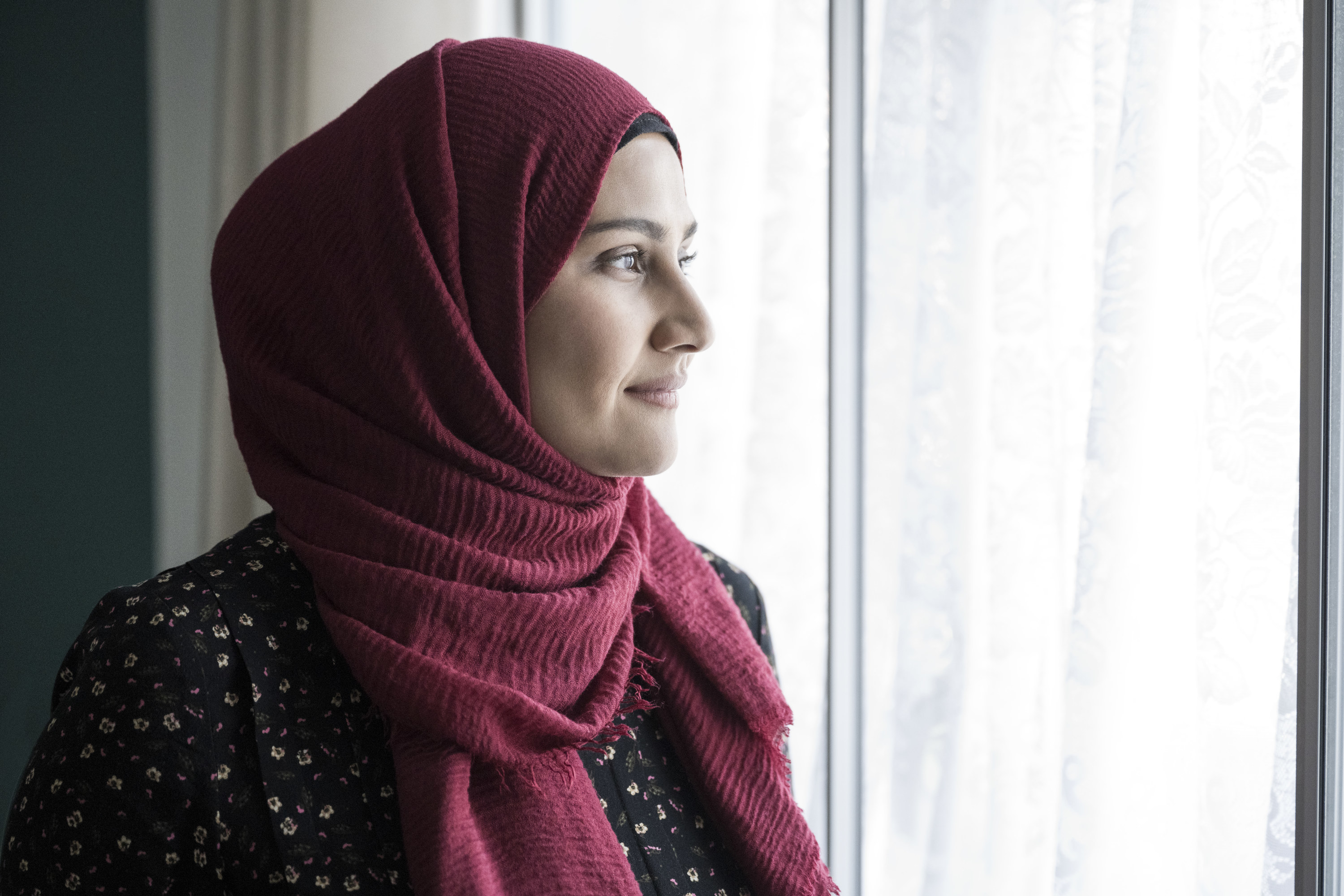 Woman wearing a head scarf looking out the window