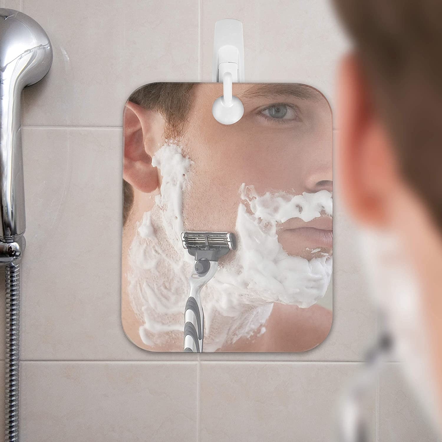 A person uses the mirror to shave their face while in the shower