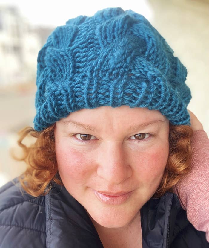 A closeup of Erica slightly smiling while wearing a knitted beanie