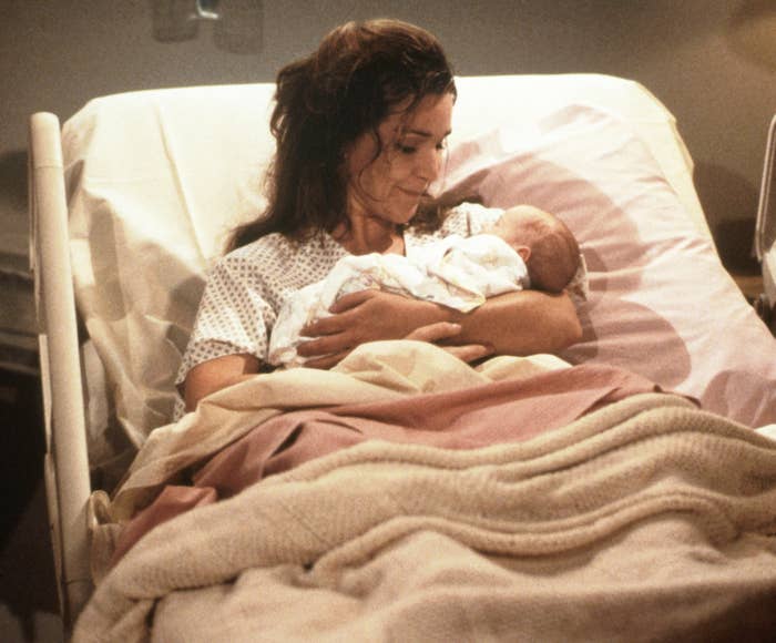 A woman holds a baby in a hospital bed