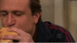 Jason Segel as Marshall from How I Met Your Mother eating a burger and looking euphoric
