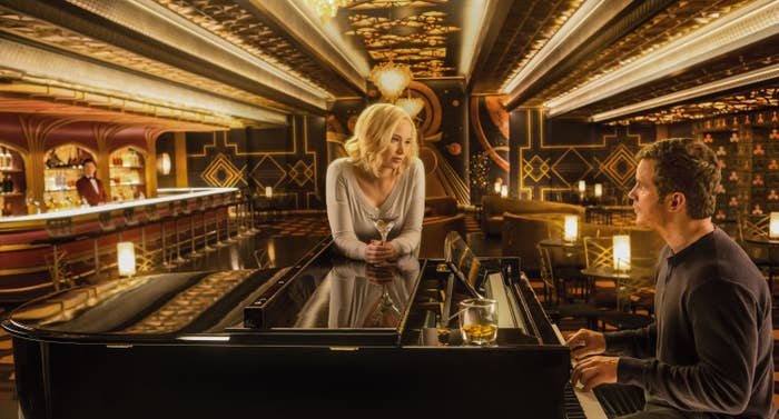 Chris Pratt and Jennifer Lawrence looking at each other while Chris plays piano