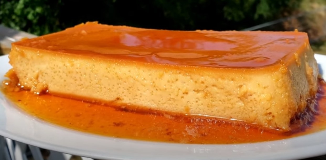A rectangular flan on a plate with a pool of caramel sauce at the base