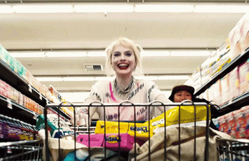 Harley Quinn from Birds of Prey pushing a cart full of products while running down the aisle of a grocery store