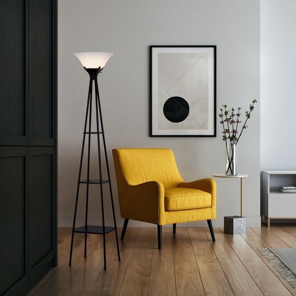 A simple black lamp in a home next to a yellow chair