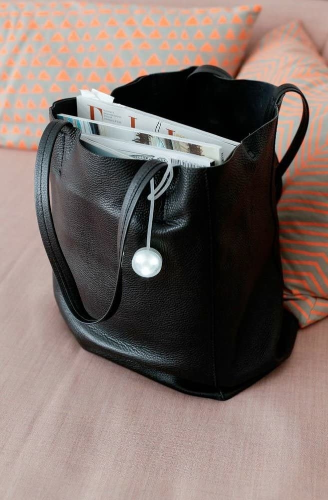 A large black tote bag with a small light hanging from the bag strap