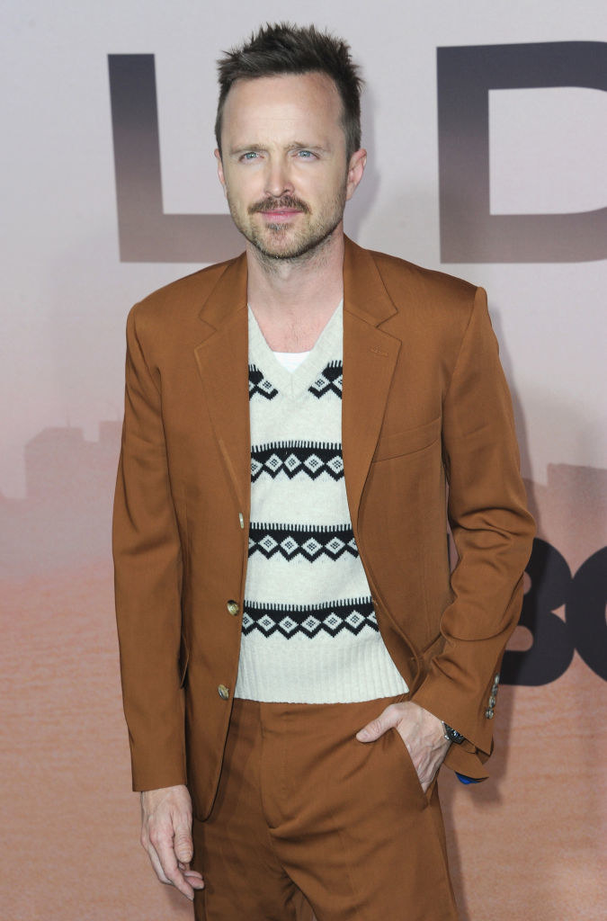 Aaron at an event with a sweater underneath a suit, and his hand in his pocket
