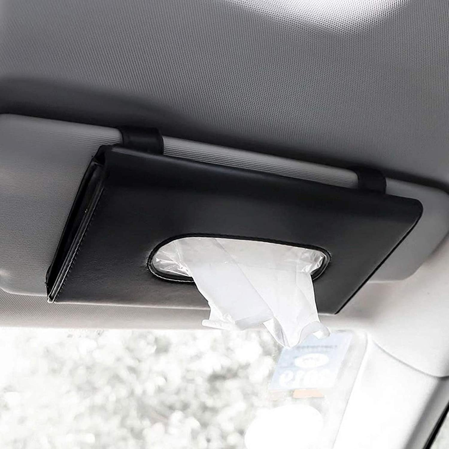 Someone pulling a tissue out of the dispenser that&#x27;s hooked onto the passenger side sun visor