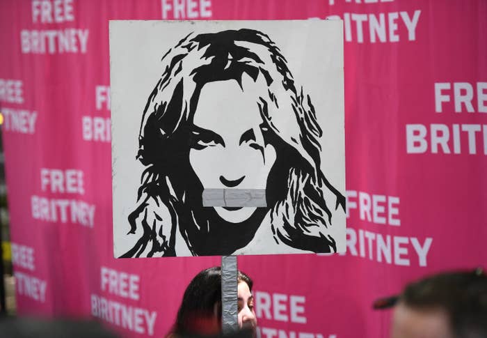 A woman holds a poster of Britney Spears with her mouth taped shut as fans and supporters gather outside the Los Angeles County Courthouse in 2021
