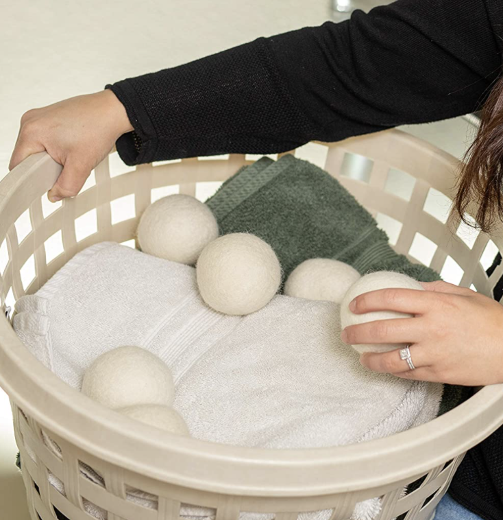Wool dryer balls in a laundry hamper that someone&#x27;s holding