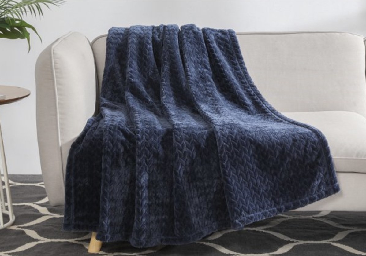 The blue textured throw blanket draped over a couch