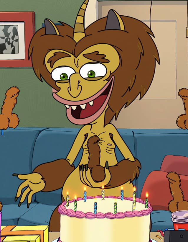 Maury sitting on a couch in front of a birthday cake with several furry penises around him