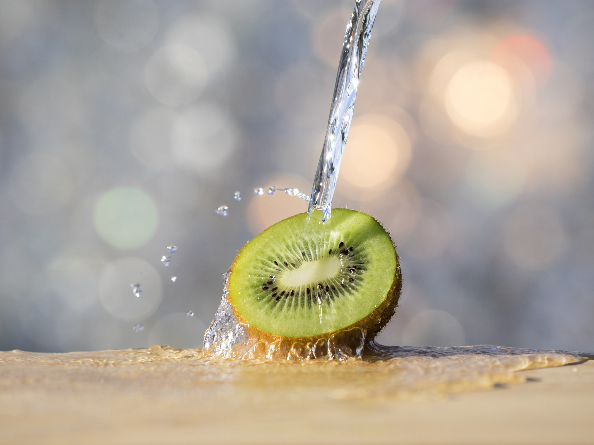 A stock image of a kiwi fruit being squirted with water