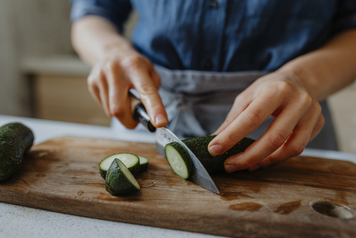 Person chopping cucumbers on a cutting board