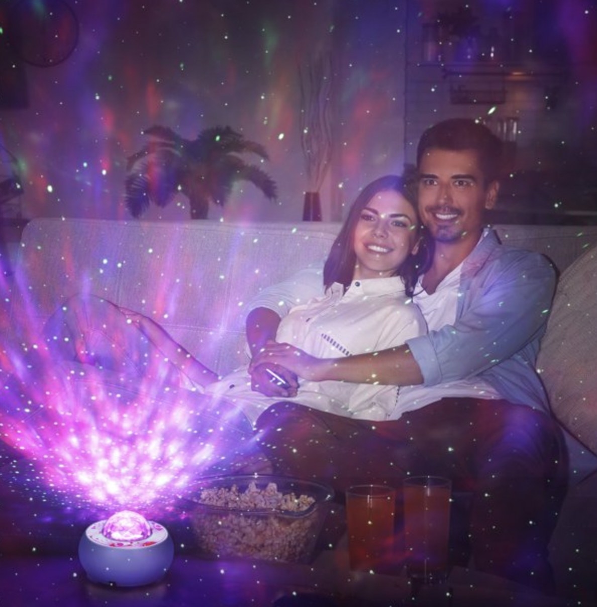 The projector emitting purple celestial light while a couple relaxes on couch together