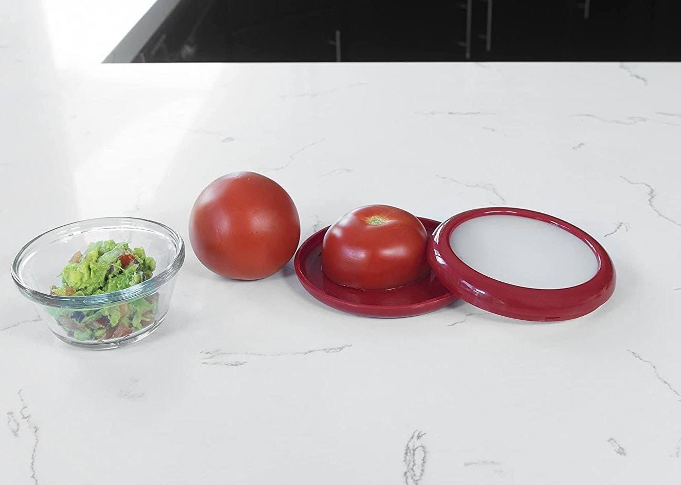 The tomato saver on a counter next to a bowl of guacamole