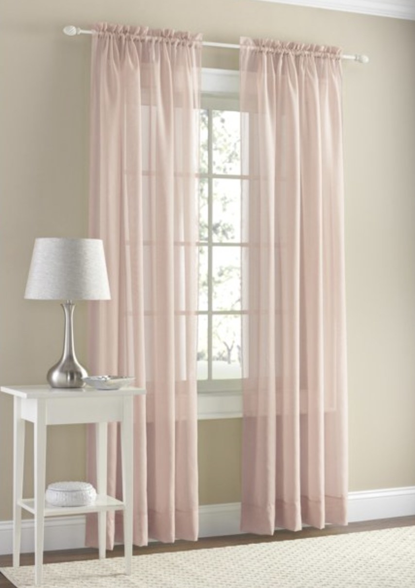 The pink curtains partially open in front of a window