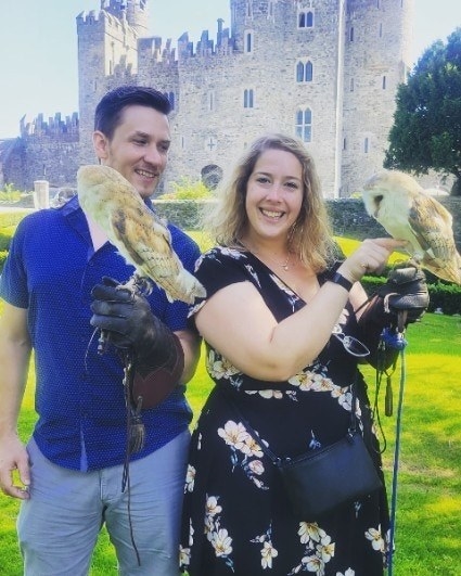 Hotels guests posing for a picture with owls perched on their gloved hands