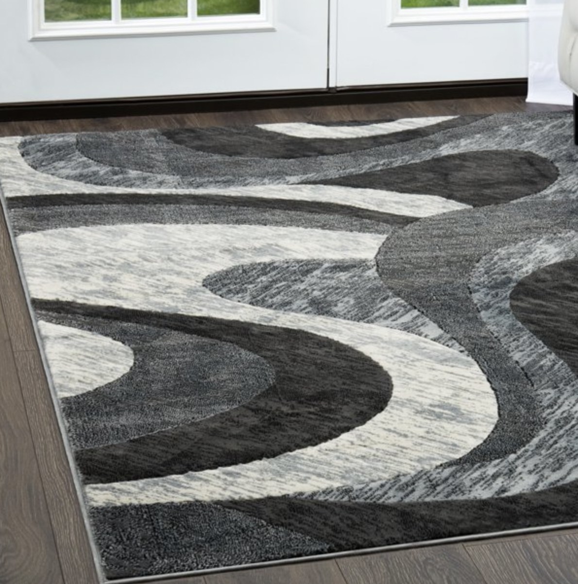 The grey and white abstract swirly-patterned area rug on a hardwood floor