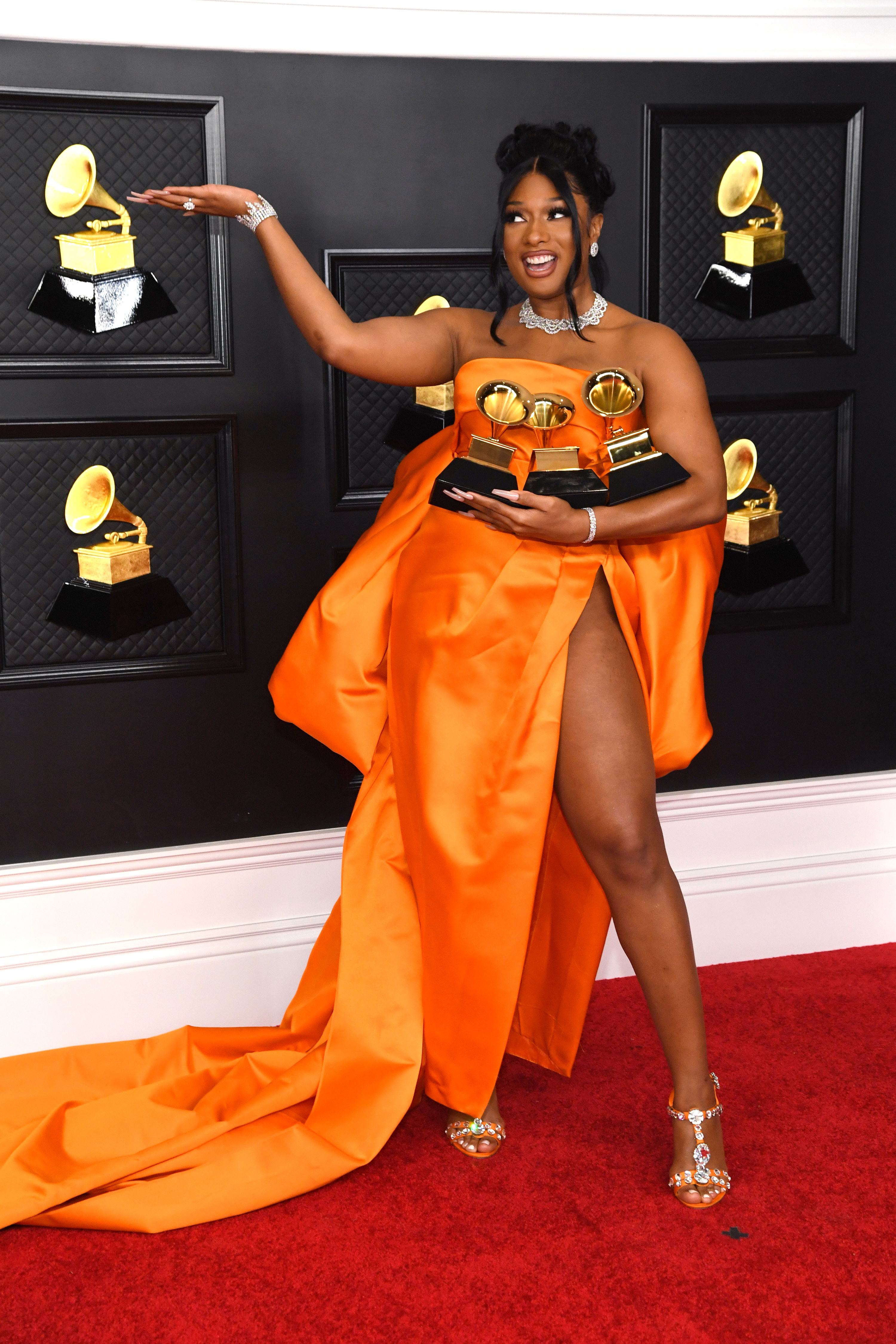 Megan poses in the strapless dress holding three of her Grammys