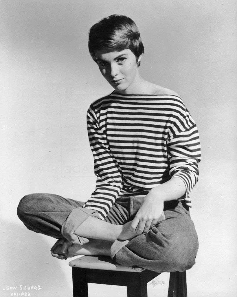 An archived photo of Jean Seberg posing criss-cross on a stool
