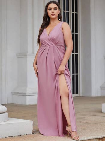 a model poses in pink and shows the side slit