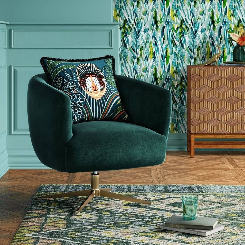 a forest green swivel armchair with a tropical patterned throw pillow