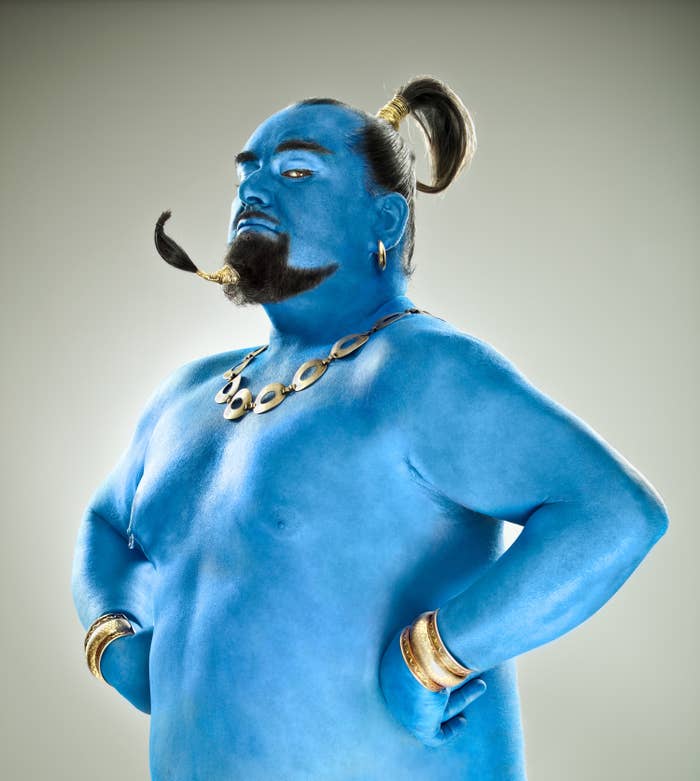 A man with blue skin, shirtless, with gold jewelry on