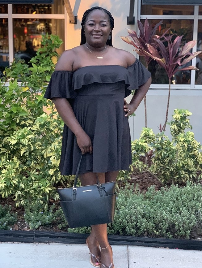 A reviewer wearing the same strapless off shoulder ruffled mini dress in black