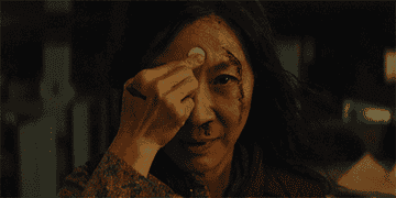 GIF of Evelyn putting a googly eye on her forehead