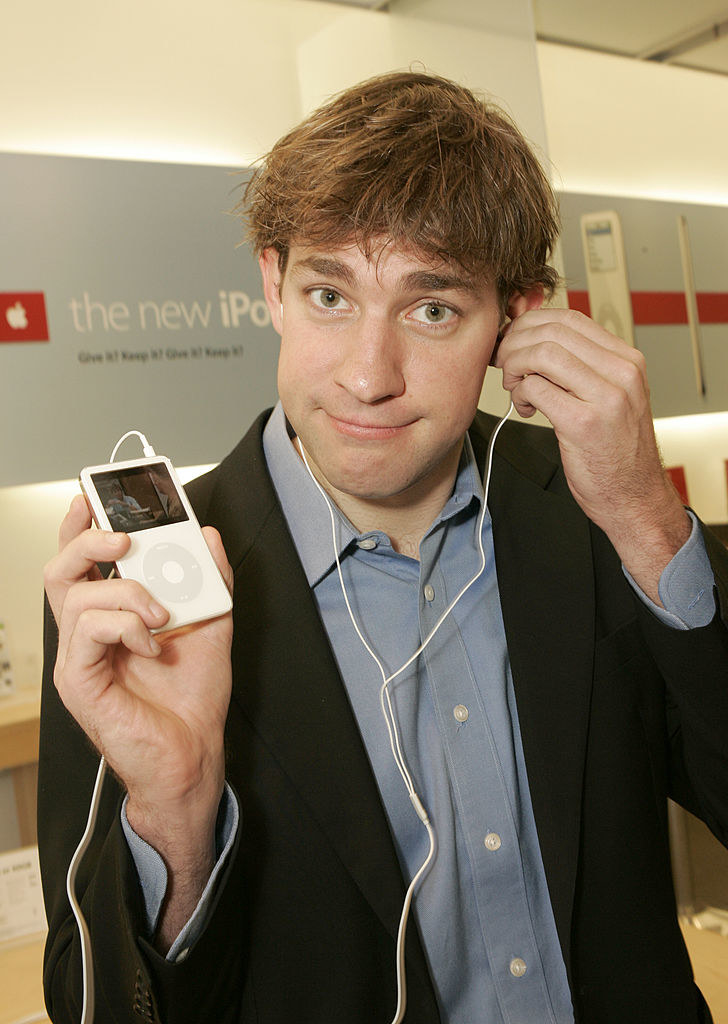 John Krasinski holding an ipod and a headphone with the other hand