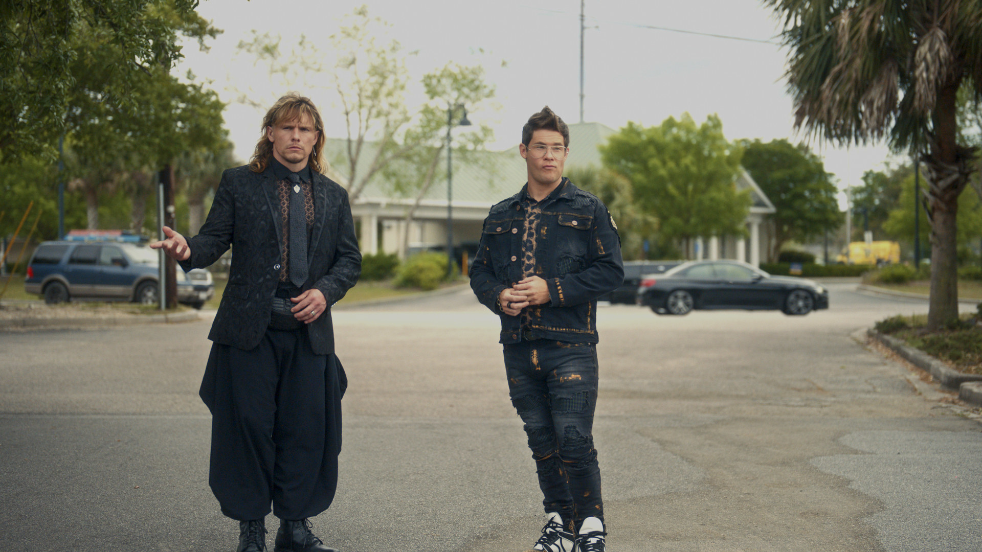 Two white men stand in a street.