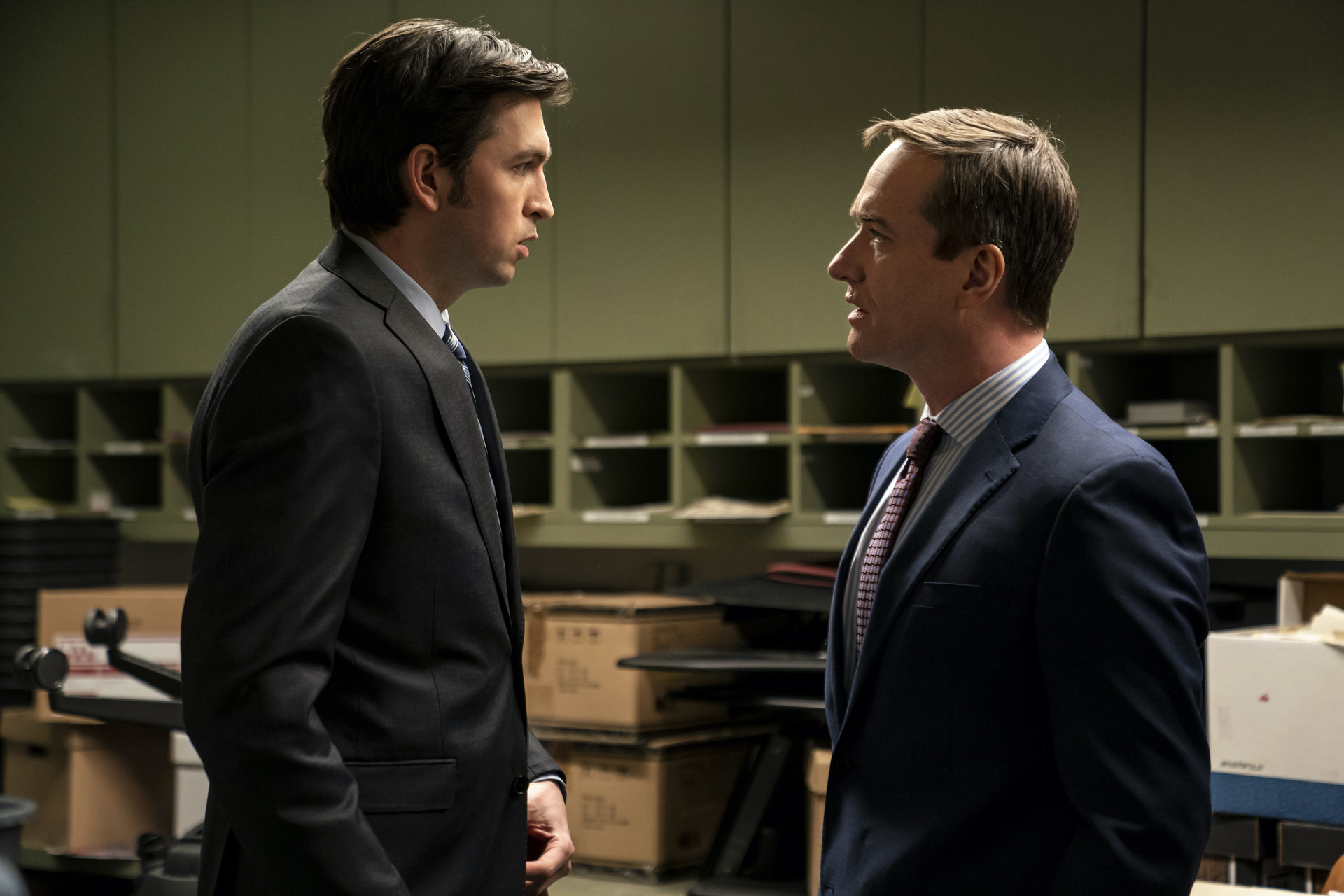 Two men in suits look intensely at each other.