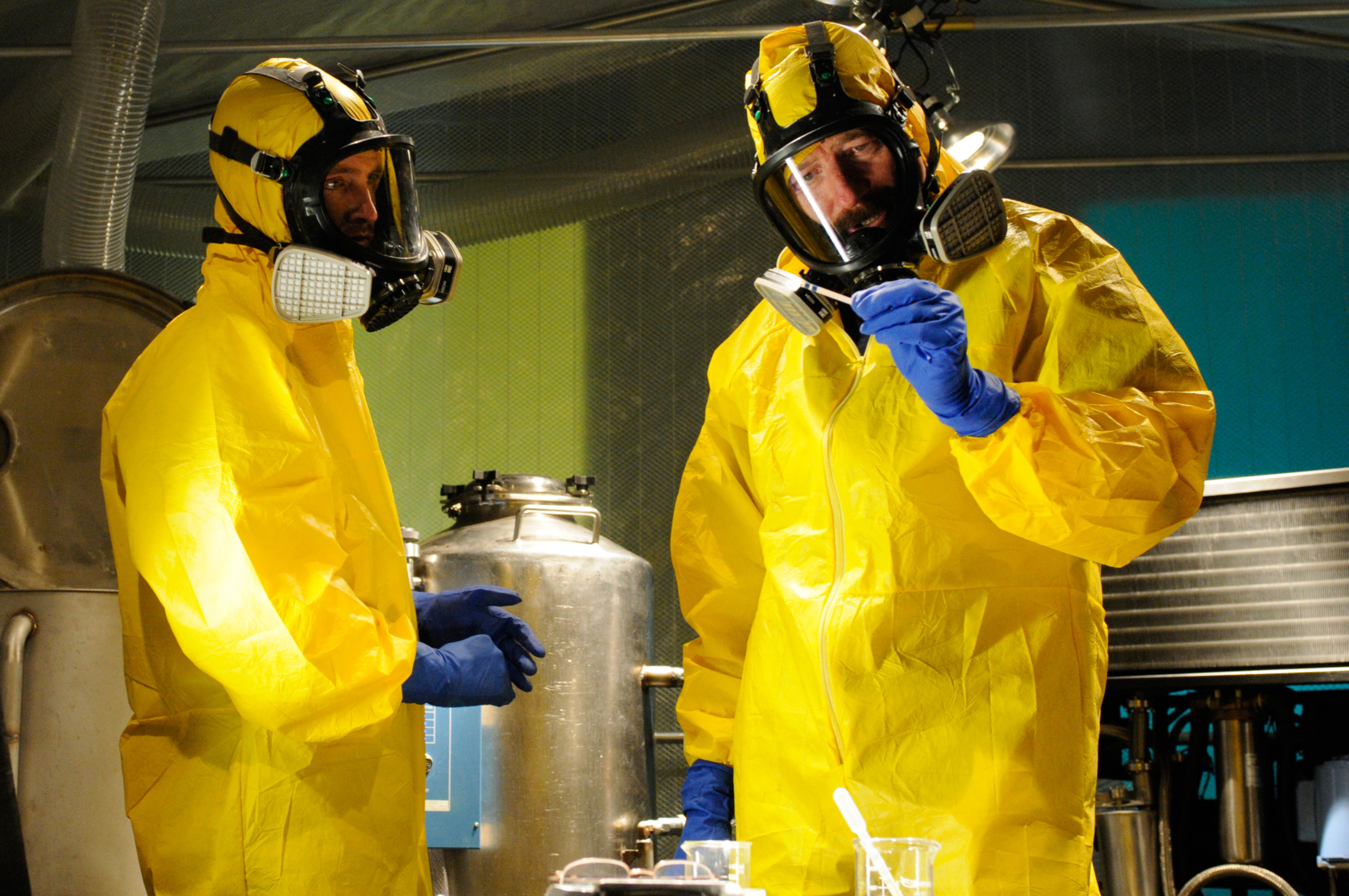 Two man stand in yellow hazmat suits.